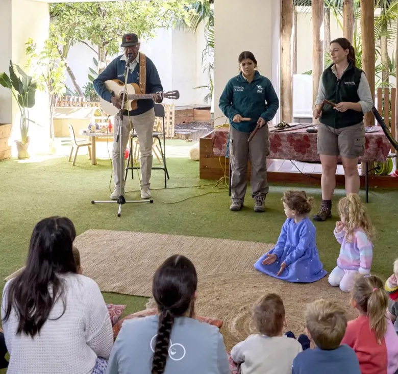 Vacation care group sitting on ground watching Animals of the Dreaming workshop performances by Colin Hardy